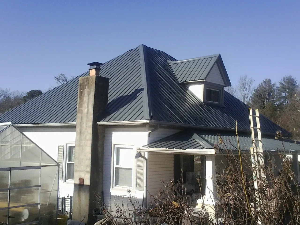 Dark blue standing seam metal roof on a white farmhouse with dormer — Slate & Tile Roof Repair by Roofing Brothers in Pilot Mountain