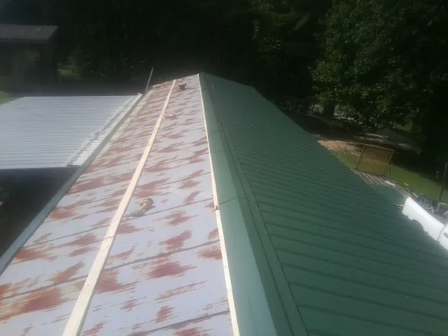Old rusted panels beside newly installed green metal roofing — Wind Damage Roof Repair by Roofing Brothers in Pilot Mountain