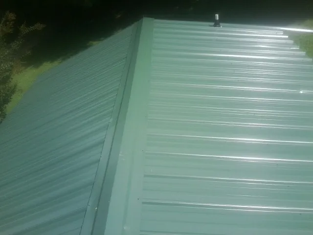New green metal panels meeting at the ridge of a roof — Flat Roof Repair work by our crew in Pilot Mountain