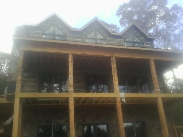 Dormers and porch framing on a large log home under construction — Roof Coating work by our crew in Pilot Mountain