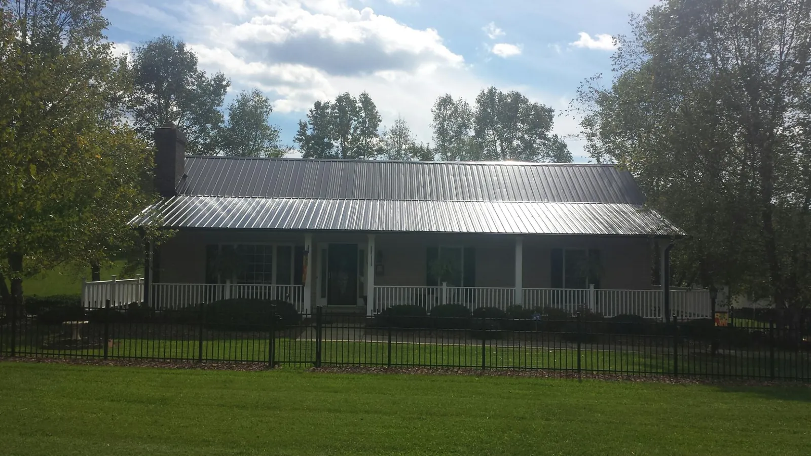 Gray metal roof on a brick ranch with a full width front porch — Gutter Guard Installation work by our crew in Pilot Mountain