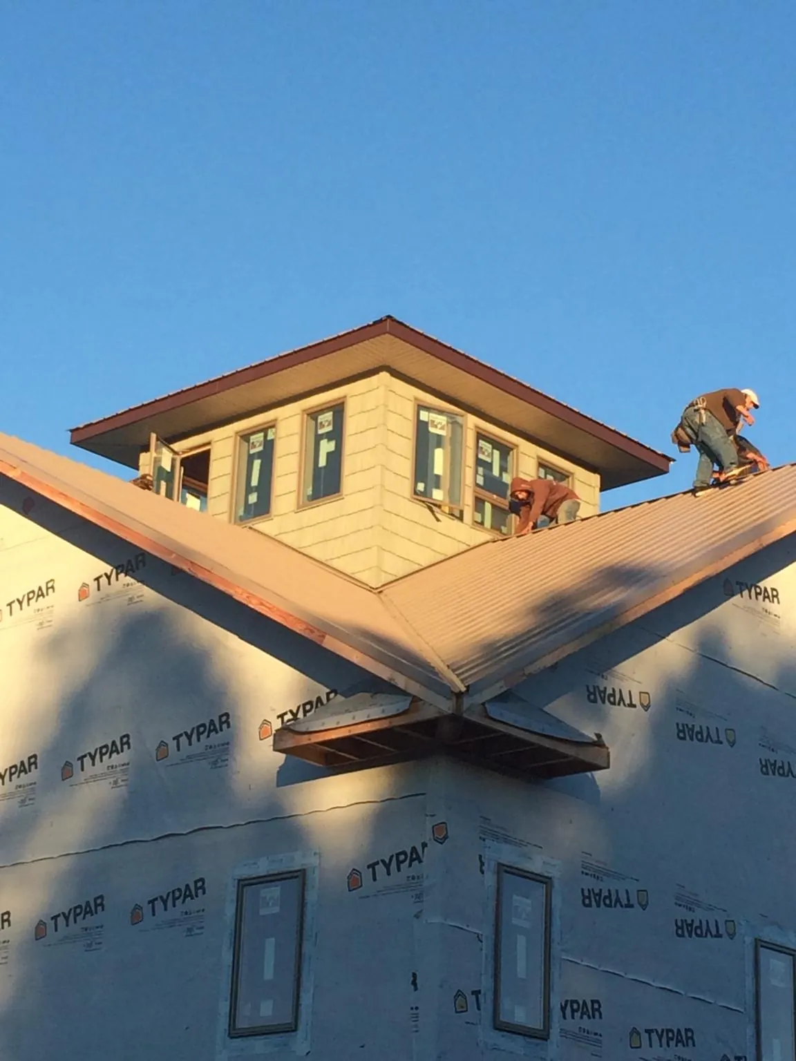Roofers working around a rooftop cupola on a new metal roof at sunset — Roof Waterproofing in Pilot Mountain by Roofing Brothers